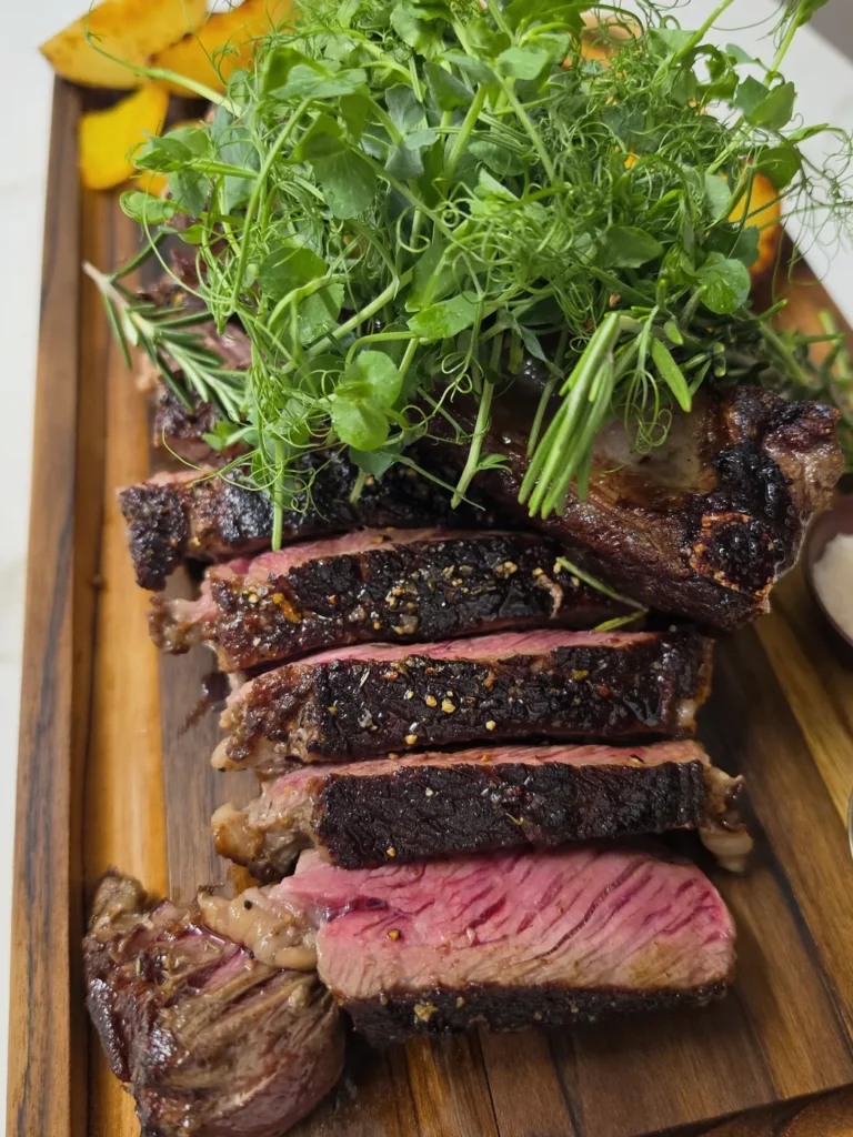 Aufgeschnittenes Steak auf dem Holzbrett mit frischer Kresse